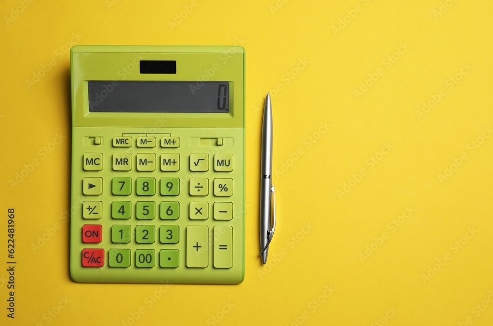 Calculator and pen on yellow background, flat lay with space for text Calculator and pen on yellow background, flat lay with space for text