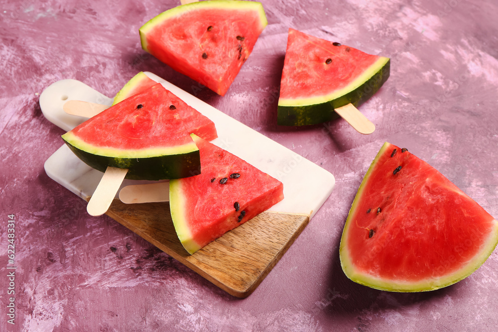Board with sweet watermelon sticks on purple background
