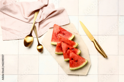 Board with pieces of fresh watermelon on white tile background