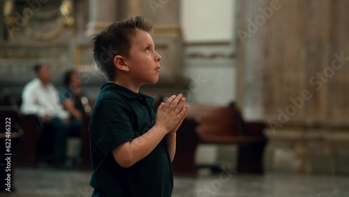 Niño latino rubio hispano Rezando orando meditando con devoción hincado de rodillas en basilica de zapopan templo cristiano católico santuario parroquia iglesia photo