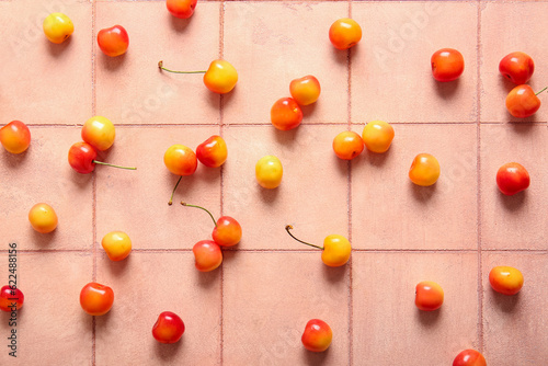 Many sweet yellow cherries on pink tile background