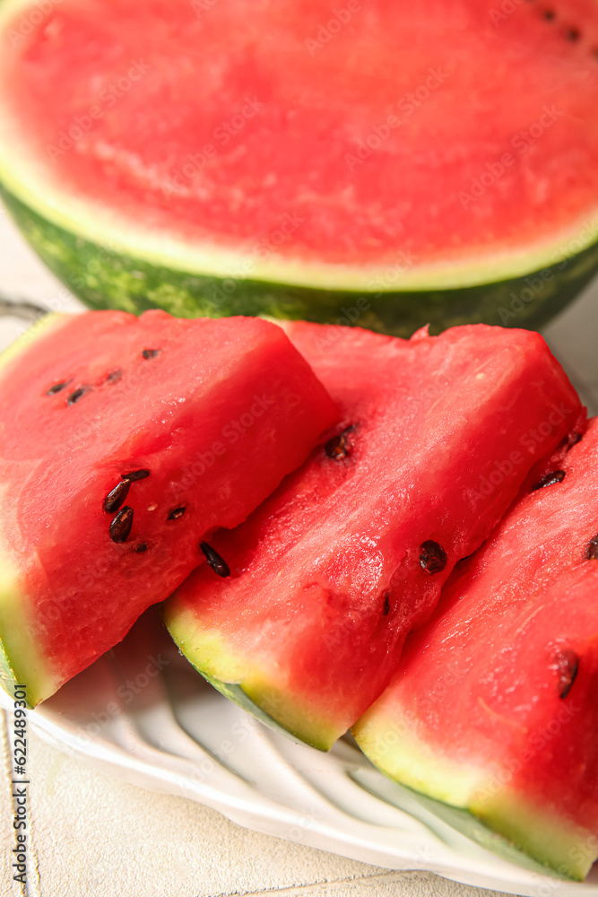 Half of fresh watermelon and plate with pieces on table, closeup Half of fresh watermelon and plate with pieces on table, closeup