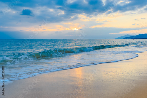 Sunset on the Sanya beach, the sun shines through the clouds on the golden sea and beach © 拾海月