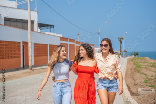 Three friends having fun and walking hugging each other © Guillermo Spelucin