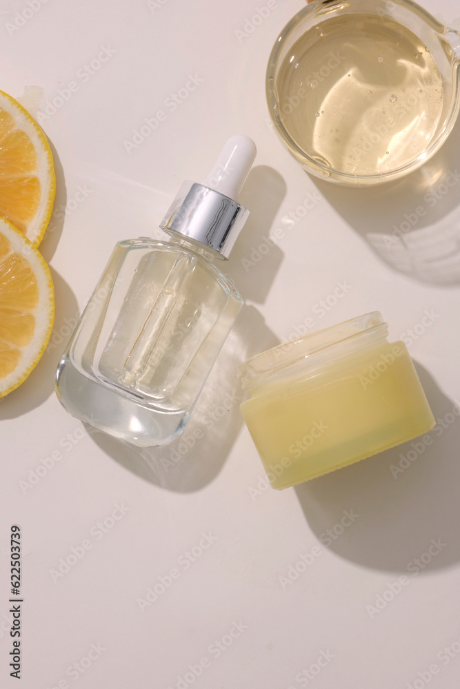 Glass dropper bottle displayed with a yellow jar and a bowl of essential oil extracted from Lemon (Citrus limon). Mockup of serum skin care cosmetic of beauty facial Glass dropper bottle displayed with a yellow jar and a bowl of essential oil extracted from Lemon (Citrus limon). Mockup of serum skin care cosmetic of beauty facial