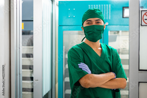 male doctor wearing medical scrubs standing with crossed hands in a lab room