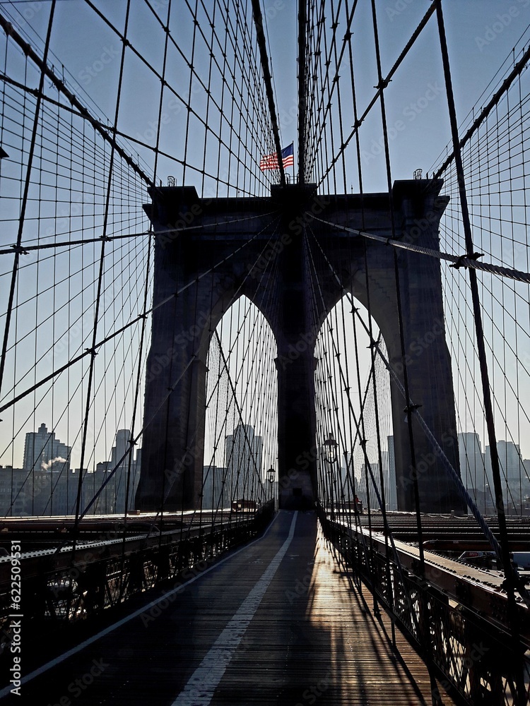 Fototapeta premium New York Brooklyn Bridge with Old Glory in the back light and blue sky