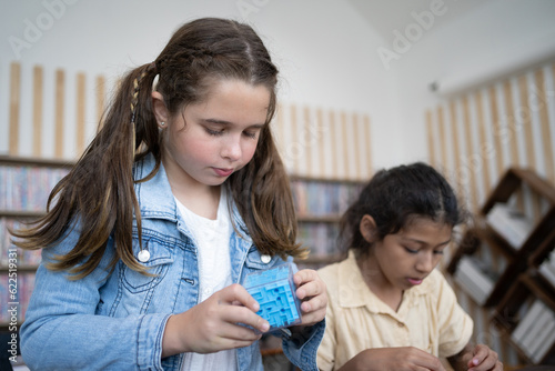 Girl playing with game sitting on table on School classroom.