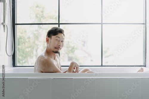Funny hilarious expression of asian man in the bathtube try to be sexy.