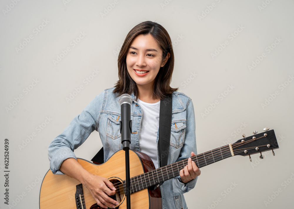 Happiness young asian woman singing song with guitar. Artist vocalist singer on isolated background. Confident woman public speaking talking with microphone in studio. Happiness young asian woman singing song with guitar. Artist vocalist singer on isolated background. Confident woman public speaking talking with microphone in studio.