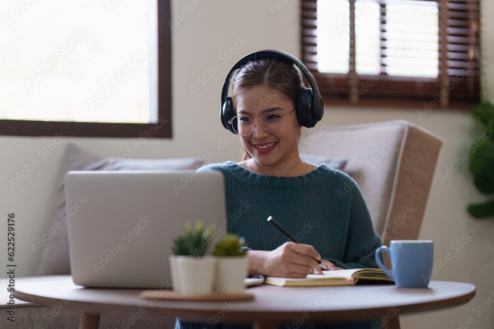 Young asian relaxed smiling pretty woman relaxing with laptop at home. Female feeling joy enjoying with mobile phone on cozy couch Young asian relaxed smiling pretty woman relaxing with laptop at home. Female feeling joy enjoying with mobile phone on cozy couch