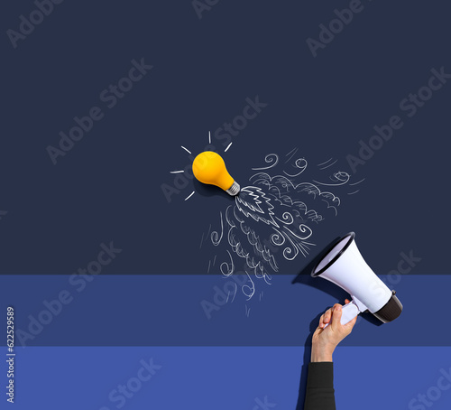 Attention and announcement concept with an idea light bulb flying to the sky like a rocket - Flat lay