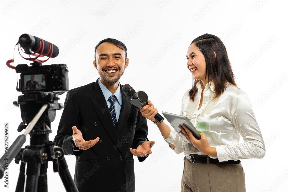 Obraz premium an adult men in black suit talking to the camera while interviewed by a beautiful female journalist using a microphone
