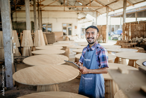 Asian businessman using tablet while standing with wood craft shop in the background