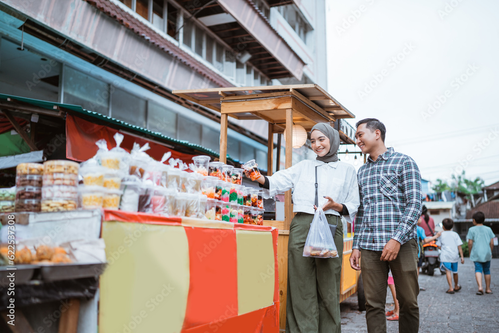 beautiful muslim couple are shopping in a food stall or street vendor during ramadan