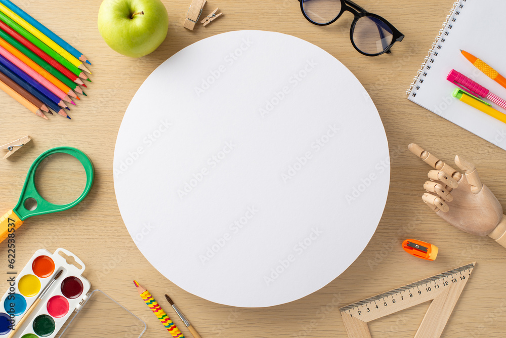 Unlock your full potential with this top-view composition showcasing an impressive range of stationery essentials against wooden backdrop, empty circle ideal for adding text or promotional messages.