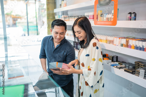 couple of shopkeeper comparing the spesification between two vape mods at the vape store photo