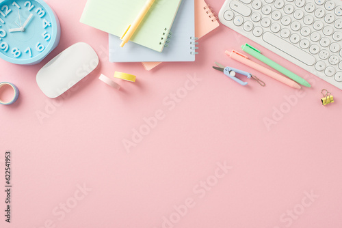 Set yourself up for success! Top view of back-to-school items like copybooks, pens, clock, computer mouse, keyboard, and more on a pastel pink surface. Add text or ads for maximum impact