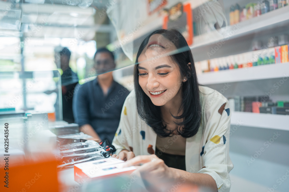 female seller smiling while picking the vape mod inside the display table female seller smiling while picking the vape mod inside the display table