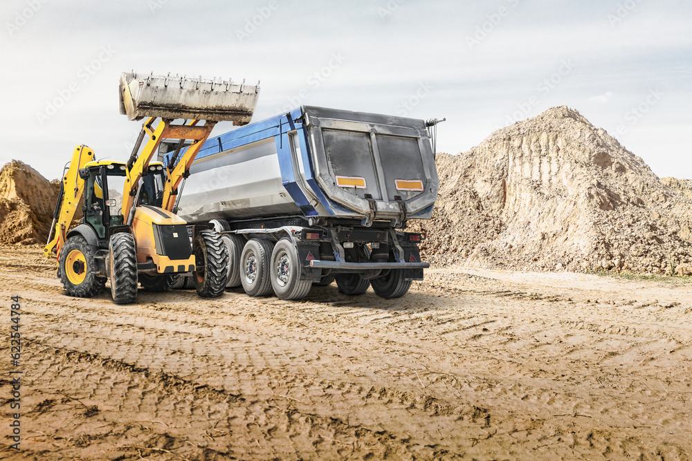 Obraz premium Modern construction machinery at a construction site in a quarry. Powerful modern equipment for earthworks. Rental of construction equipment. Excavator, dump truck, bulldozer, loader.