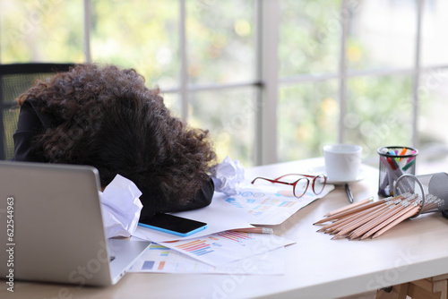 Mid adult businesswoman lying face down on table in office after bad news business failure or get fired and feeling discouraged, distraught, distraught and hopeless in modern office.