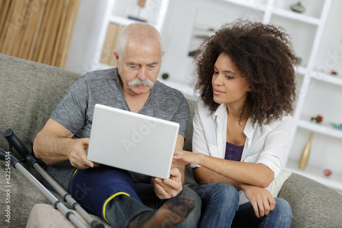 homecarer with elderly woman using laptop computer