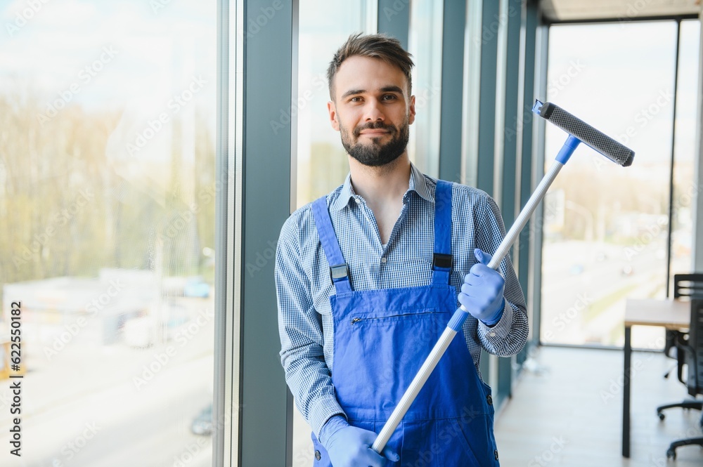 Young man cleaning window in office Young man cleaning window in office