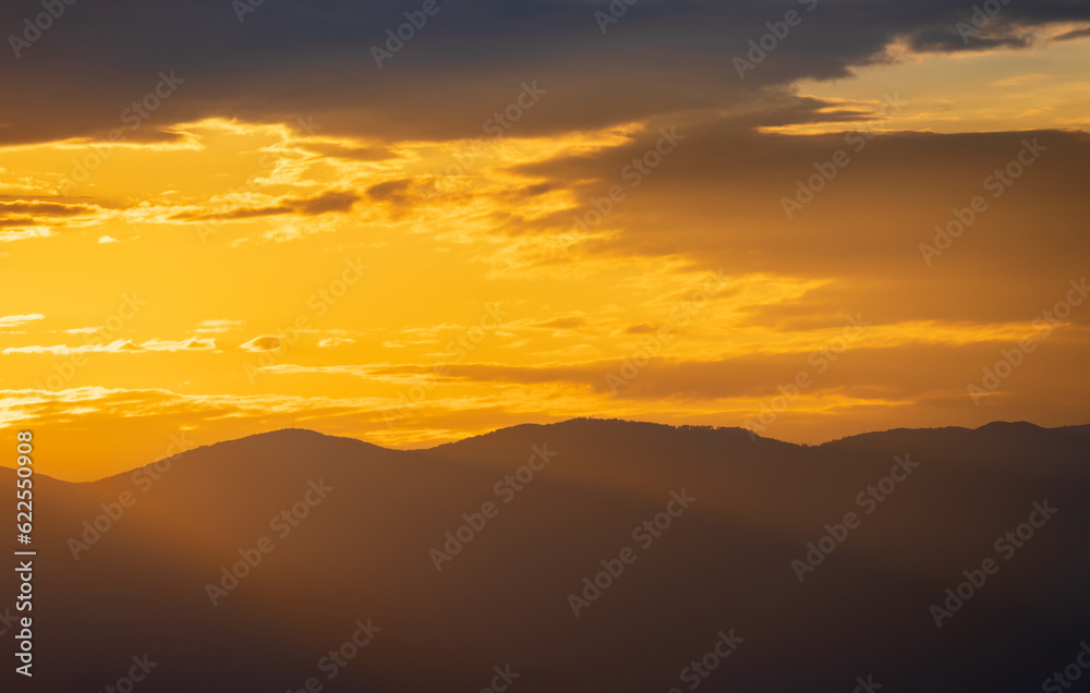 Sunset sky with light beams shine through distant hill. Travel, nature background, Croatia, island Krk