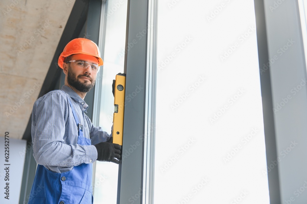 Worker installing plastic window indoors. Worker installing plastic window indoors.