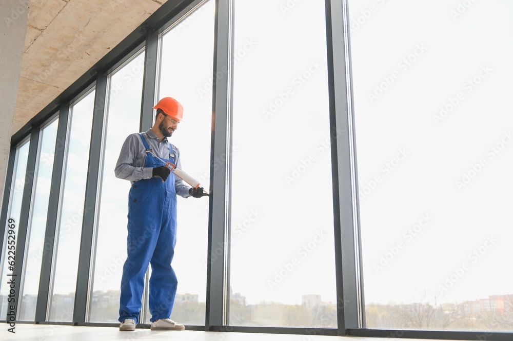 Worker installing plastic window indoors. Worker installing plastic window indoors.