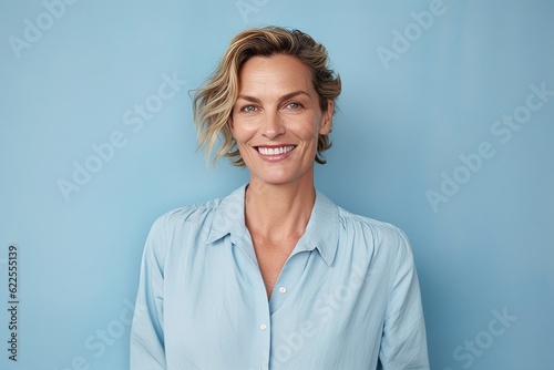 Portrait of a smiling businesswoman standing against blue background and looking at camera
