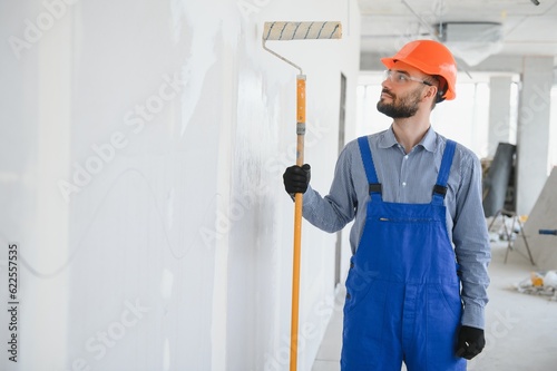 Painter in uniform paints the wall.