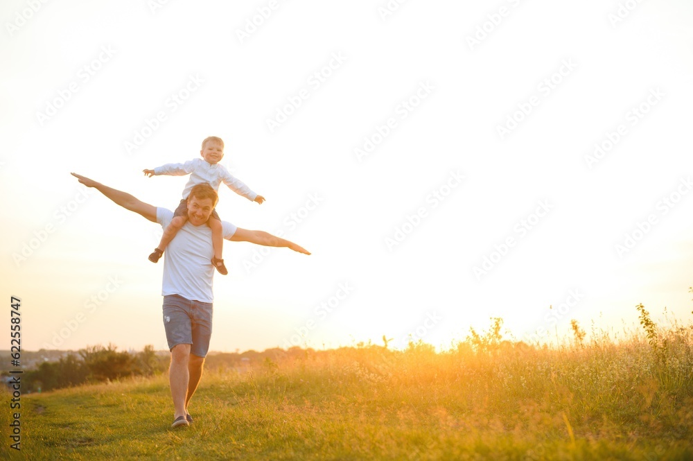 Father's day. Happy family father and toddler son playing and laughing on nature at sunset Father's day. Happy family father and toddler son playing and laughing on nature at sunset