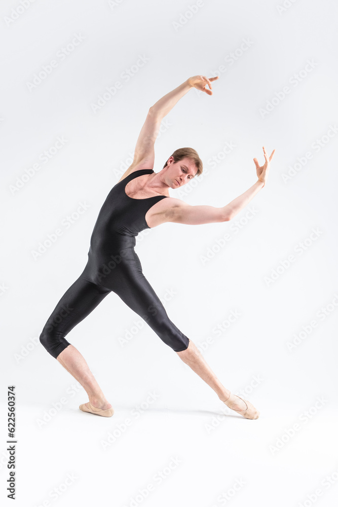 Obraz premium Professional Ballet Dancer Young Caucasian Athletic Man in Black Suit Posing Stretching in Studio On White With Lifted Hands.
