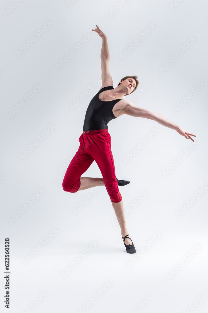 Obraz premium Ballet Sport Ideas. Contemporary Ballet of Flexible Athletic Man Posing in Red Tights in Dance Pose With Hands Lifted in Studio on White.