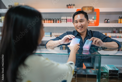 female customer with long black hair choosing the variant of the vape mod that offered by the male seller