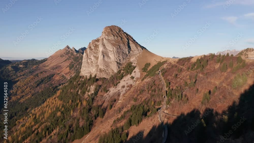 Drone flying over treetops towards steep mountain slope with train track