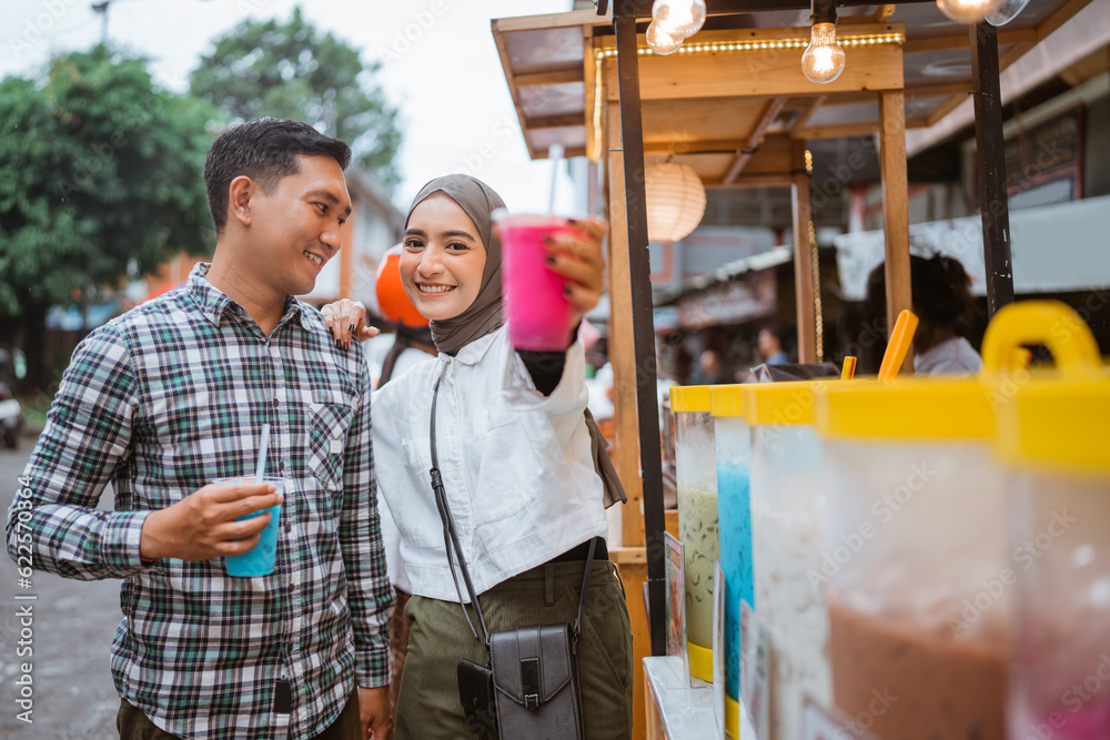 portrait of happy young muslim couple buy drink from a street vendor
