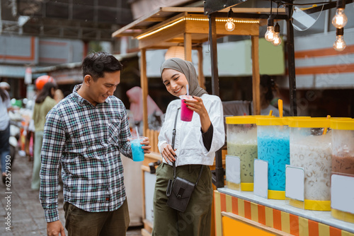portrait of happy young muslim couple buy drink from a street vendor © Odua Images
