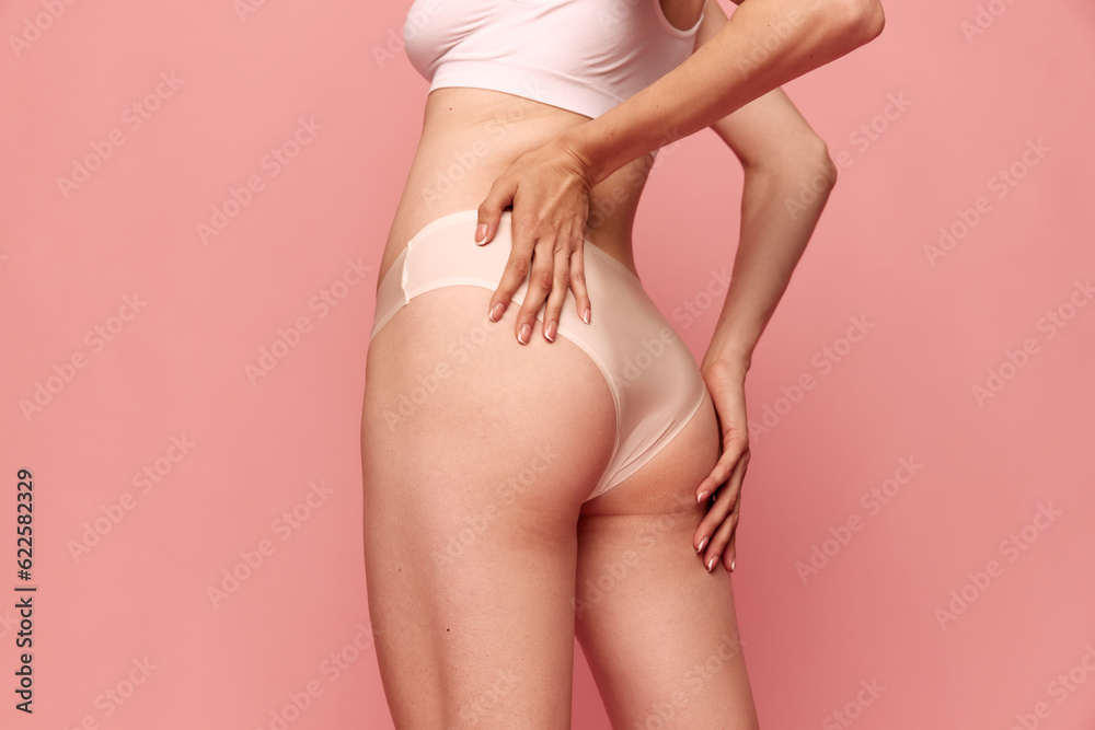 Cropped image of female body, buttocks in underwear against pink