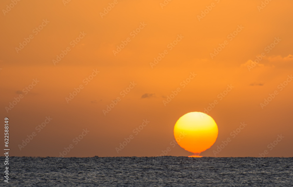 magic sunrise with a burning and torn orange sun at the horizon from the red sea