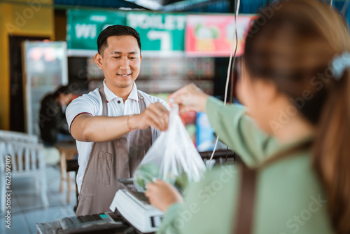 male seller putting the plastic bag on the scale to scalling it on cashier photo