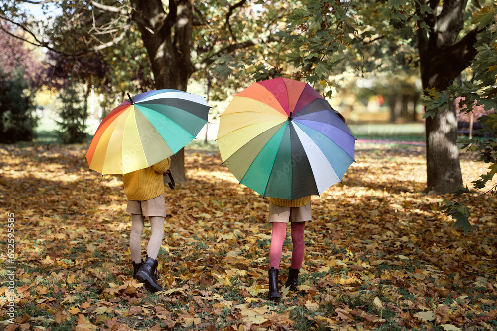 Rear view of sisters walking with colorful umbrella