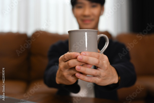 Select focus on hands of male hands holding a mug of of tea or coffee