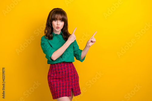 Photo of sweet impressed lady wear green shirt lips pouted plump pointing two fingers empty space isolated yellow color background