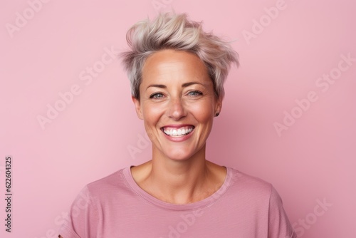 Murais de parede Portrait of a smiling middle-aged woman with short blonde hair on a pink backgro