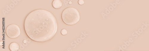 round drops of transparent gel serum on beige background 