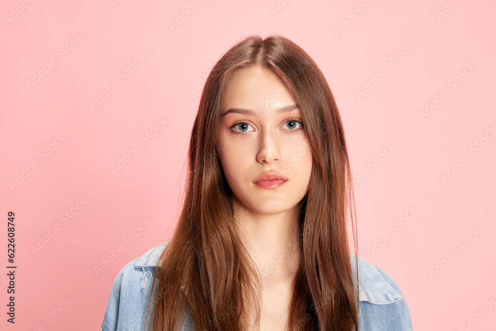 Portrait of young beautiful woman looking at camera with calm, serious expression against pink studio background. Concept of human emotions, fashion, youth, lifestyle, female beauty, ad Portrait of young beautiful woman looking at camera with calm, serious expression against pink studio background. Concept of human emotions, fashion, youth, lifestyle, female beauty, ad