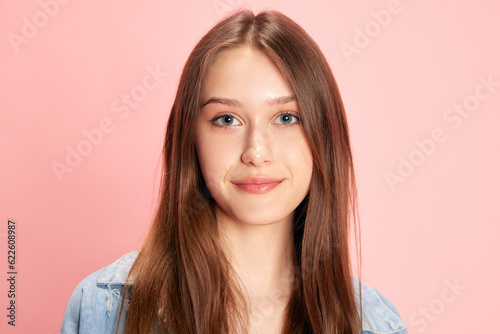 Portrait of young beautiful woman, student looking at camera and smiling against pink studio background. Positive. Concept of human emotions, fashion, youth, lifestyle, female beauty, ad © master1305