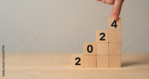 Business growth concept in 2024. Business goals and achievement. Sustainable development. Wooden cubes inscripted 2024 and growth icon on smart background. Positive indicators banner. photo